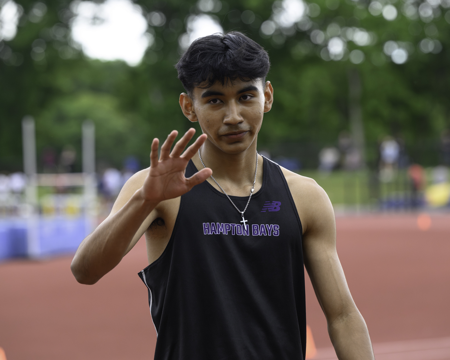 Hampton Bays senior Charlie Garcia gives a wave after winning his heat in the 100-meter dash.   MARIANNE BARNETT