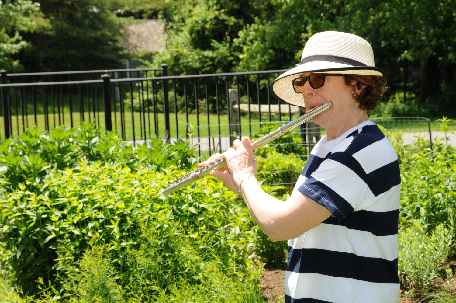 Julie Bluestone plays the flute at ChangeHampton’s “Naming Names: To Save It, We Need To Name It,” at the pollinator garden at East Hampton Town Hall in Saturday.   RICHARD LEWIN