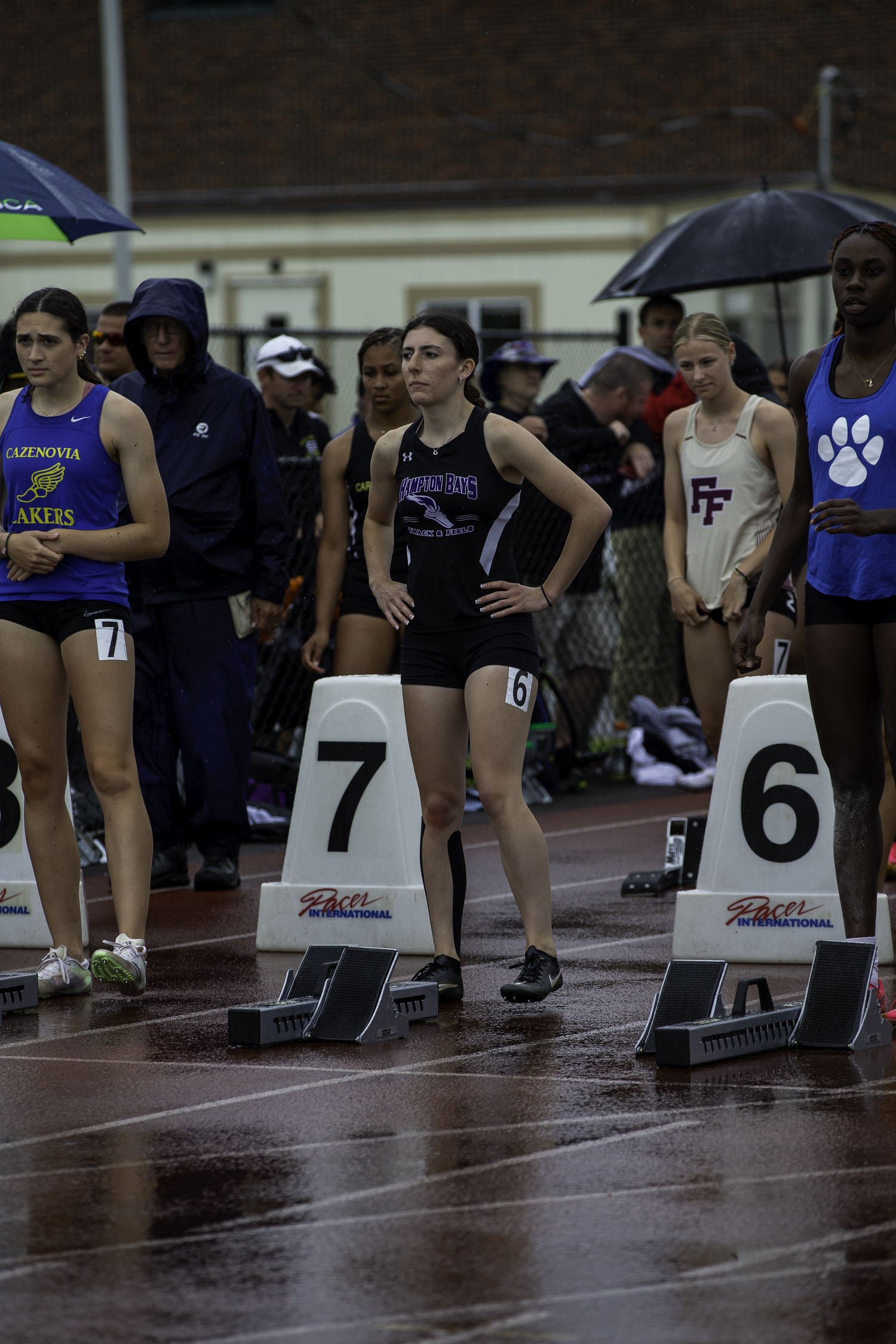 Hampton Bays senior Emma Halsey and her competitors get set to run in a soggy 100-meter hurdles at the New York State Track and Field Championships at Cicero-North Syracuse High School.   ZAIDA TALEV