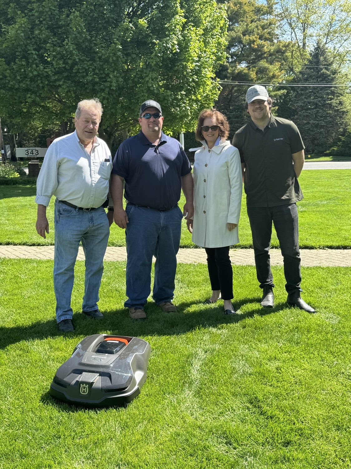 Southampton Village has partnered with
Greener, a leader in battery-operated, robotic lawn mowing that offers reduced noise, pollution and  time needed for lawncare. By replacing gas-powered, ride-on mowers with robots, Greener reduces CO2 and noise.
A second phase of ecologically forward projects is focusing on more renewable solar energy in the village, with a new solar array being installed in the parking lot behind the village ambulance barn, and another planned for the West Main Street parking lot. The village has also installed three GrowCharge Plaza benches that have charging ports.  Residents can dedicate a bench with a family name for $3,500, memorializing a place in a  sustainable future. From left, with the robot mower, consultant to the DPW, Harold Weed; Stephen Phillips Jr. DPW superintendent,; 
Deputy Mayor Gina Arresta; Greener co-founder & COO Adam Goldwasser. COURTESY SOUTHAMPTON VILLAGE